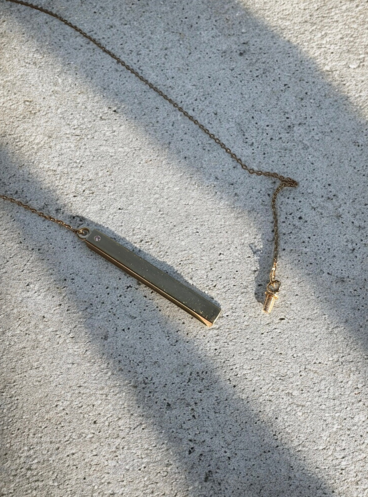 Gold bar pendant necklace with stone, shown open with screw enclosure revealing hollow interior to hold ashes 